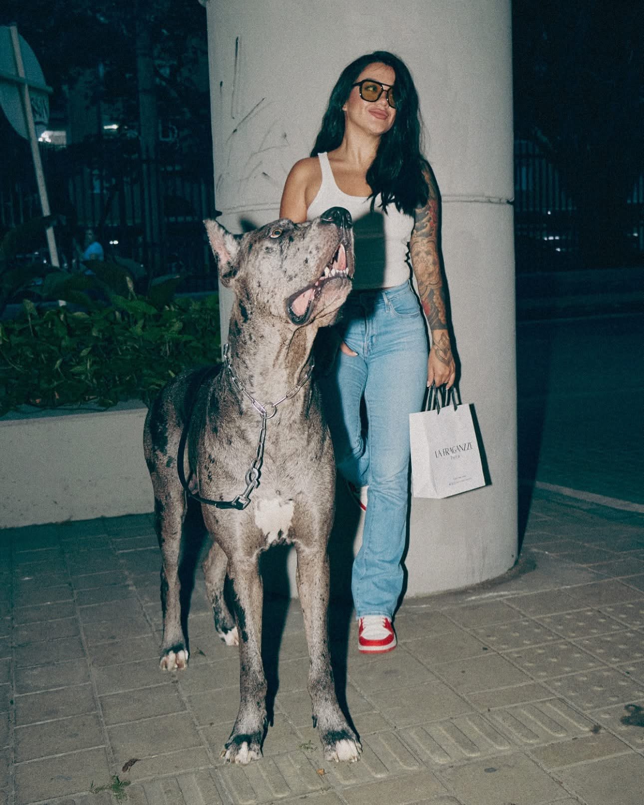 Kellie caminando de noche por Medellín junto a Salvador, que la mira hacia arriba
